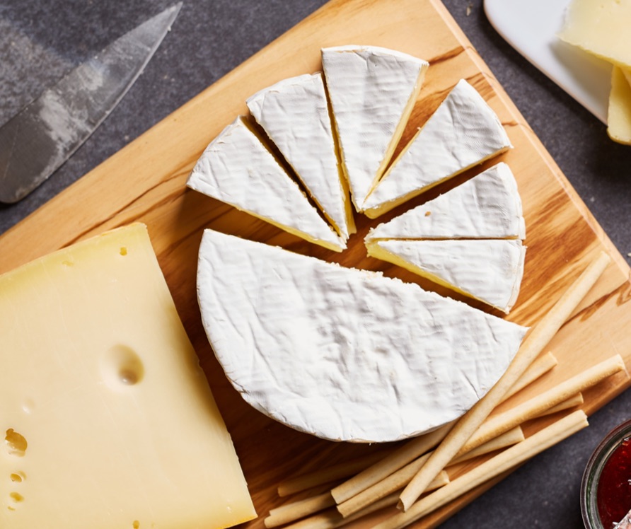 Block of cheese and cheese wheel on cutting board